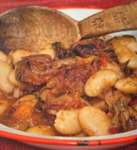 Verwarm de olijfolie in een ruime pan en smoor de gesneden uien zachtjes een aantal minuten. Voeg de knoflook uit de pers toe en de ontvelde tomaten in kleine stukjes. 